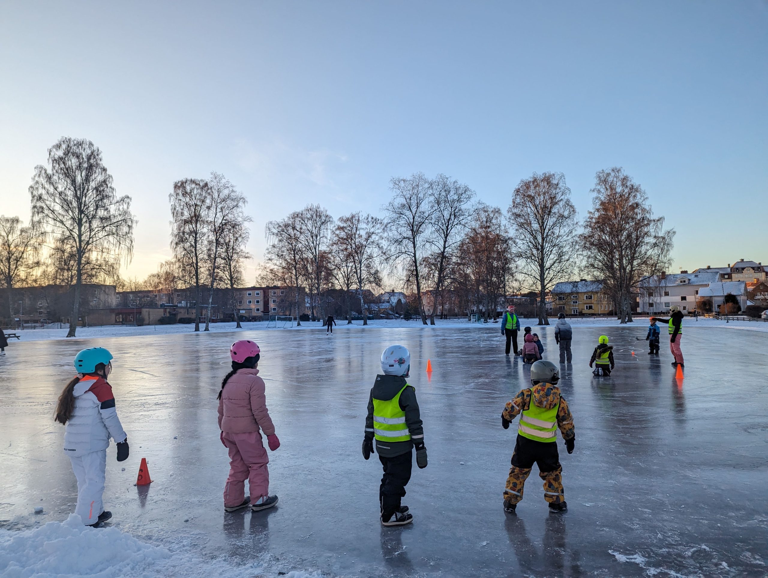 Elever med skridskor på skolgårdens isbana