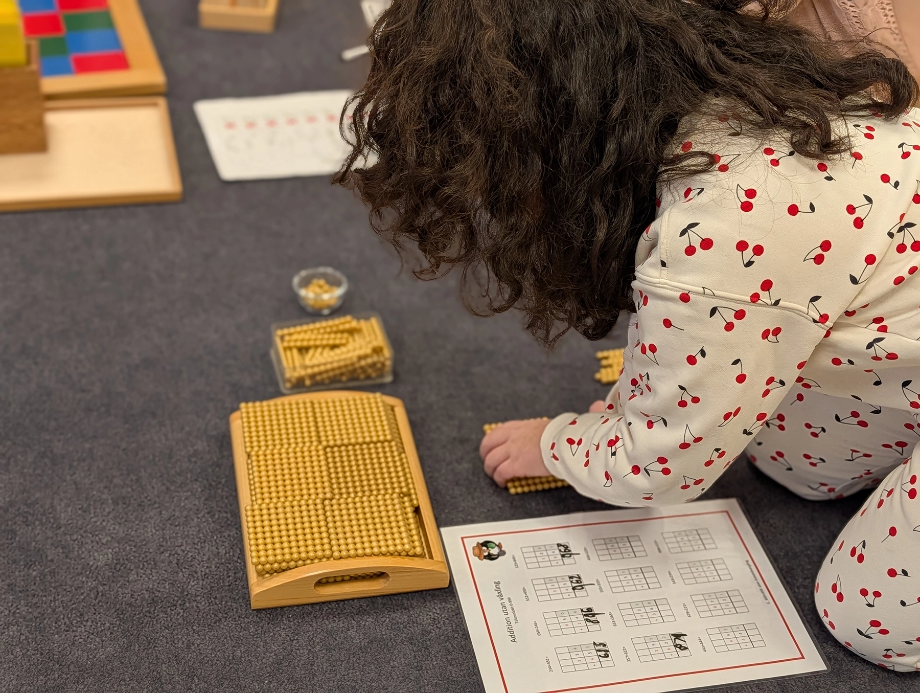 Skolelev sitter på golvet och använder sig av pärlor, ett inom montessoripedagogiken centralt och konkret material som hjälper eleverna att se matematiska begrepp på ett mer konkret ett